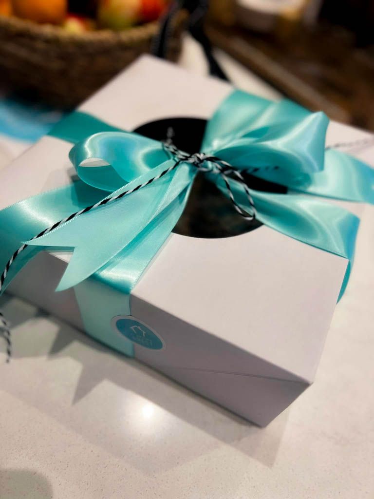 Guest welcome gift box wrapped with a teal ribbon by A Happy Host